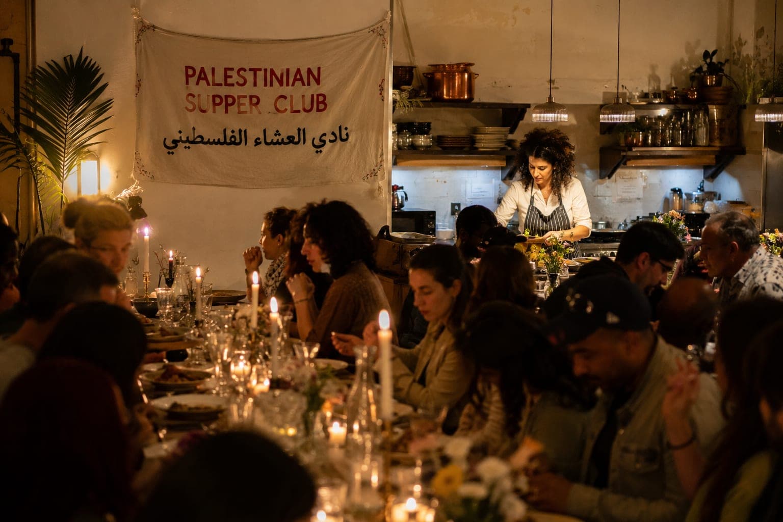 Guests sharing a candlelit dinner at a long supper-club table.